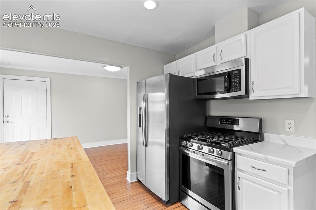 Image 9 of 31: Kitchen featuring stainless steel appliances, white cabinetry with silver-t