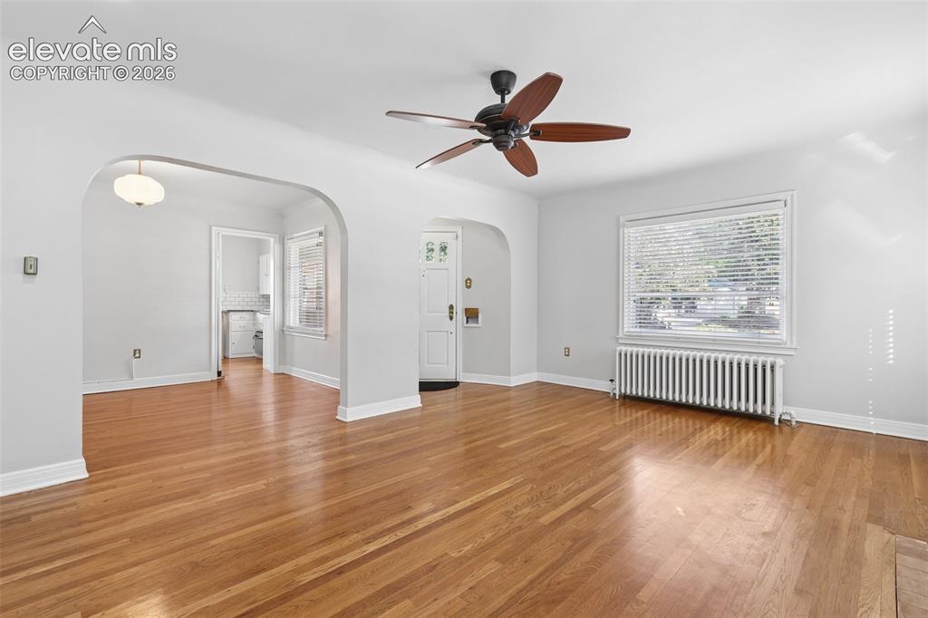 Image 14 of 50: Hardwood flooring throughout, arched doorway, ceiling fan with wood-finish
