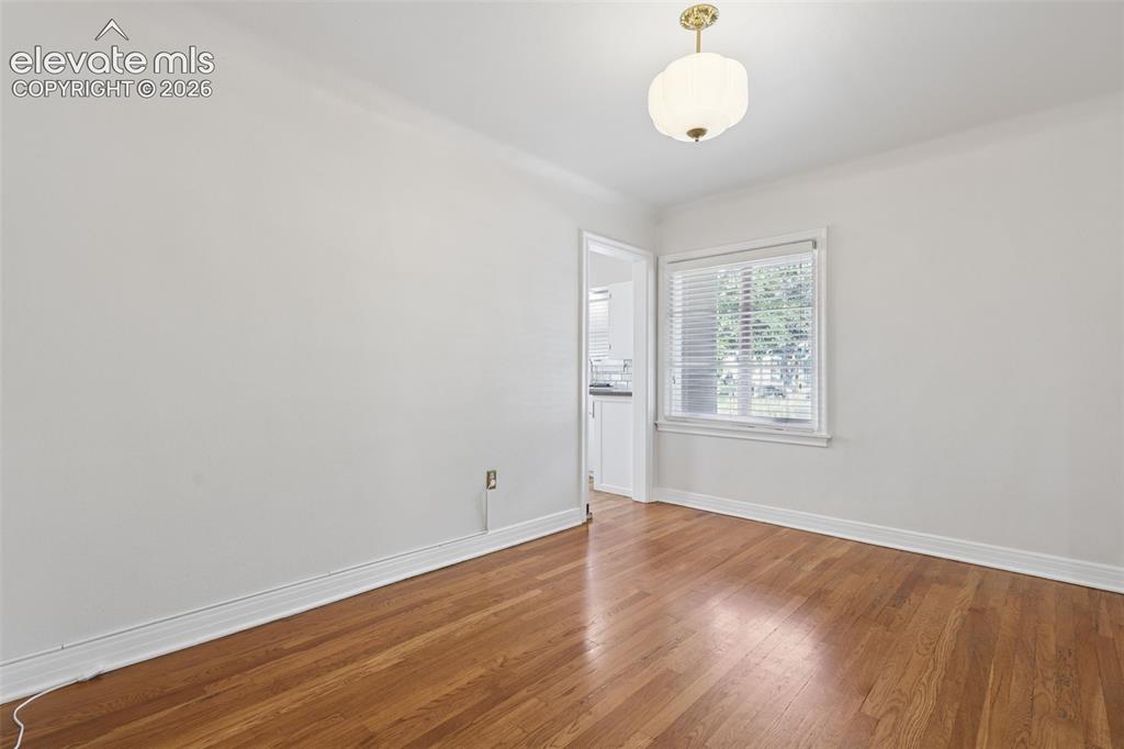 Image 16 of 50: Hardwood flooring, window with blinds, white walls, overhead light fixture,