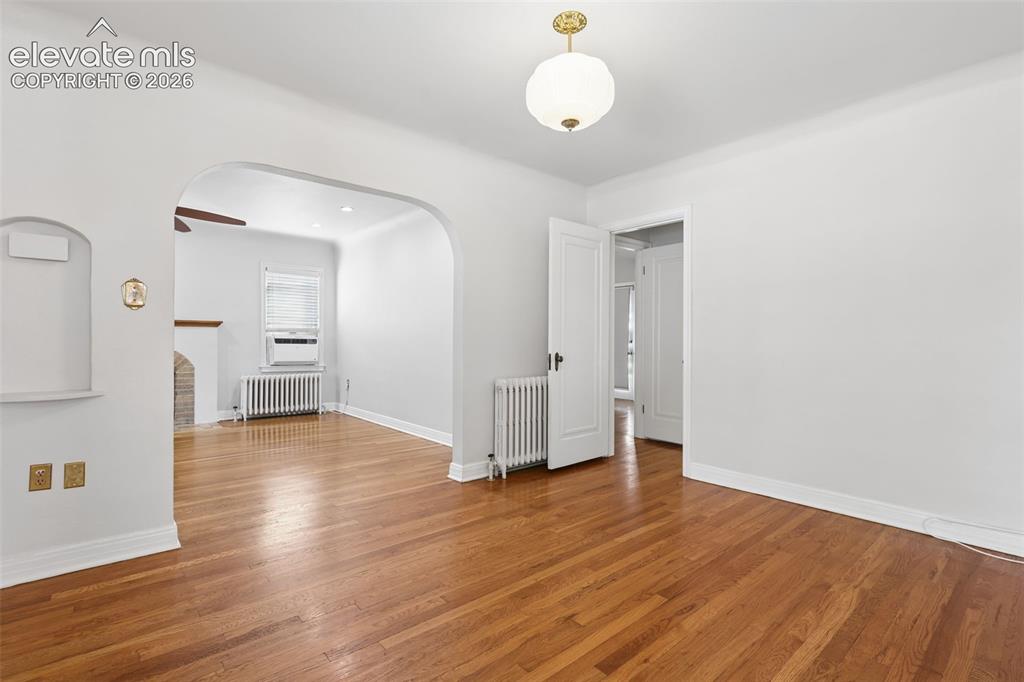 Image 17 of 50: Hardwood flooring, arched doorway, ceiling-mounted light fixture, built-in 