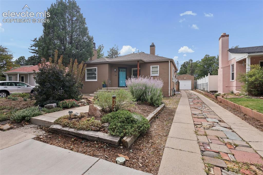 Image 2 of 50: Stucco exterior with a covered front porch, a vibrant blue entry door, and 