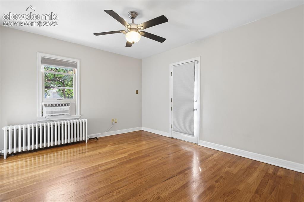 Image 21 of 50: Hardwood flooring with a ceiling fan, white trim, and a window