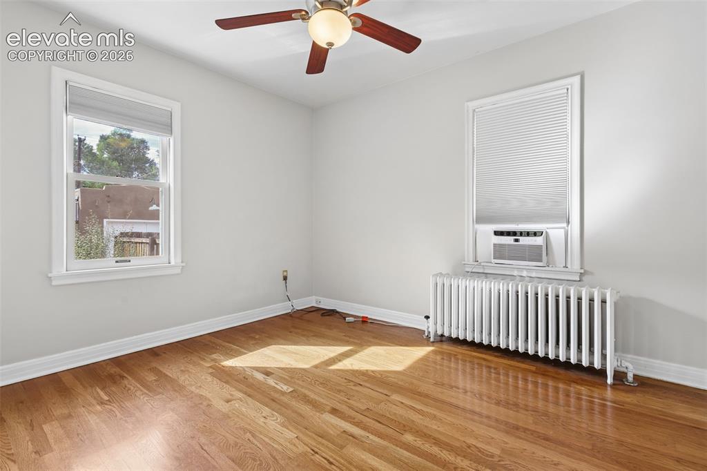 Image 24 of 50: Wood-finish flooring, ceiling fan, white window trim, window air conditioni