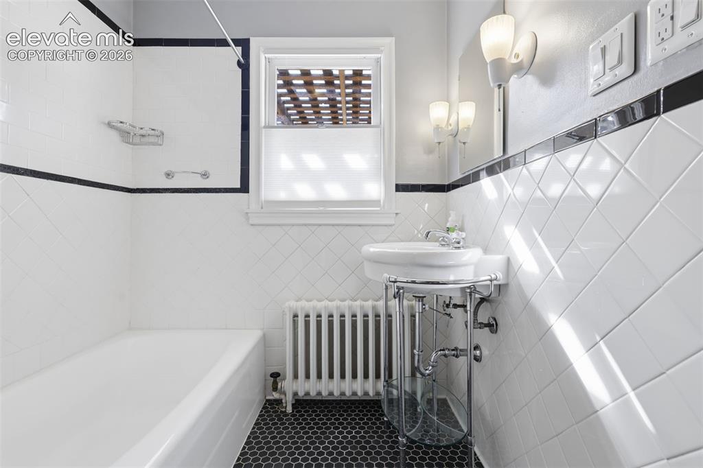Image 27 of 50: White subway tile walls with black trim, black hexagonal floor tiles, white