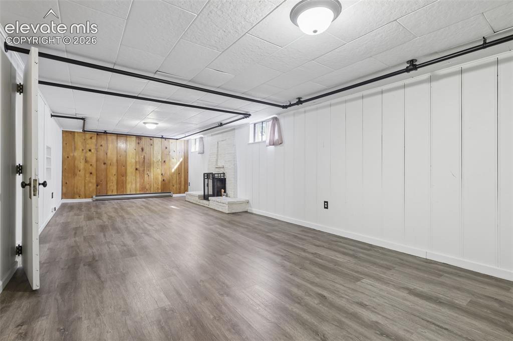 Image 33 of 50: Spacious room featuring wood-finish flooring, white panel walls, and a whit