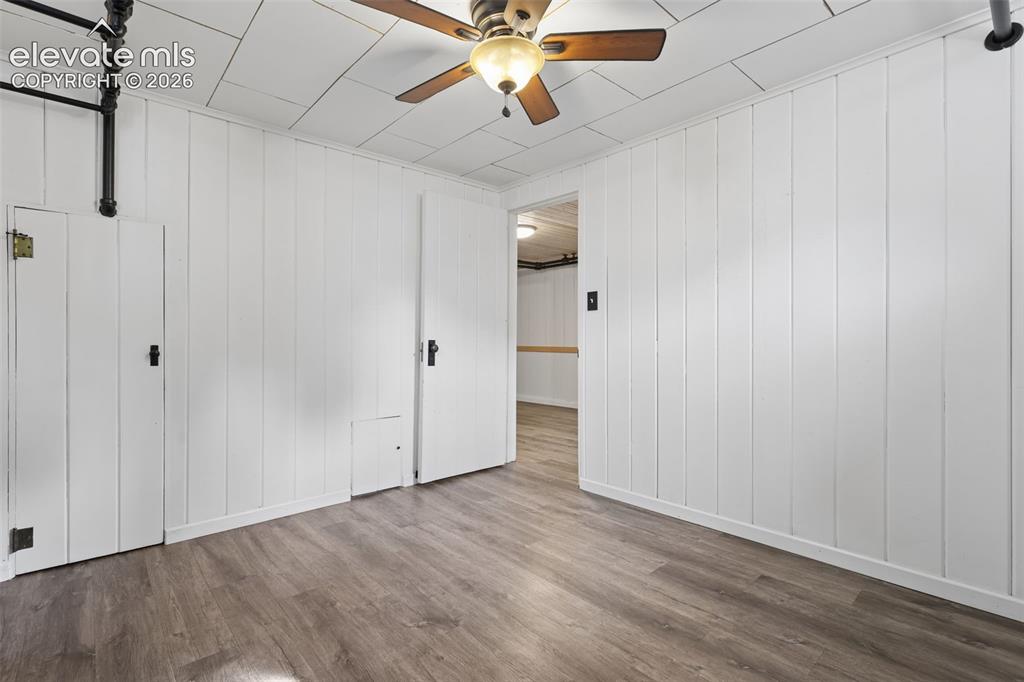 Image 34 of 50: Wood-finish flooring, white vertical paneling, white ceiling panels, ceilin