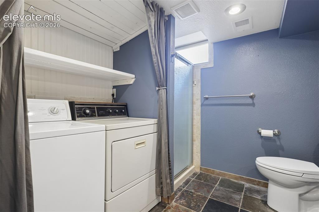 Image 36 of 50: Shower stall with frosted glass door, slate tile flooring, white toilet, an