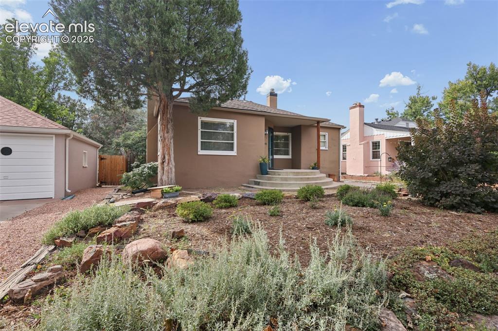 Image 4 of 50: Stucco exterior with a peaked roof, concrete steps, and a detached garage f