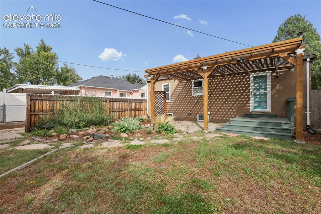 Image 41 of 50: Backyard featuring a wooden pergola, wood fence, and stone pathway