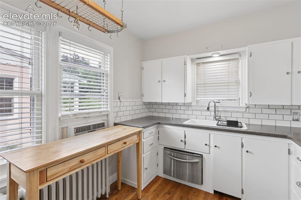 Image 6 of 50: White cabinetry with dark countertops, subway tile backsplash, and a stainl