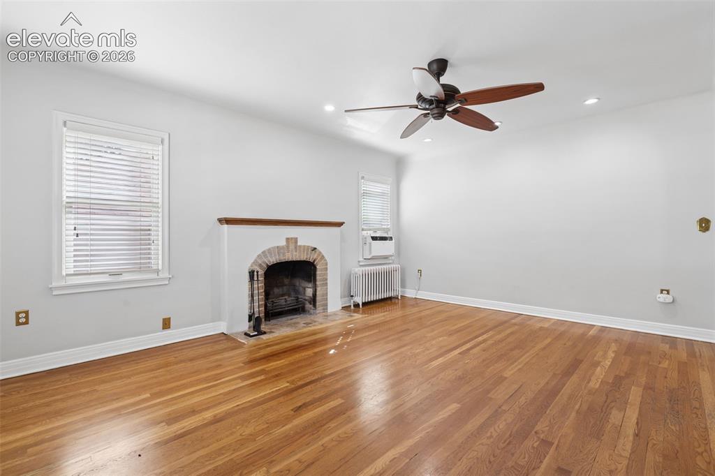 Image 8 of 50: Wood-finish flooring, brick fireplace with wood mantel, ceiling fan, recess