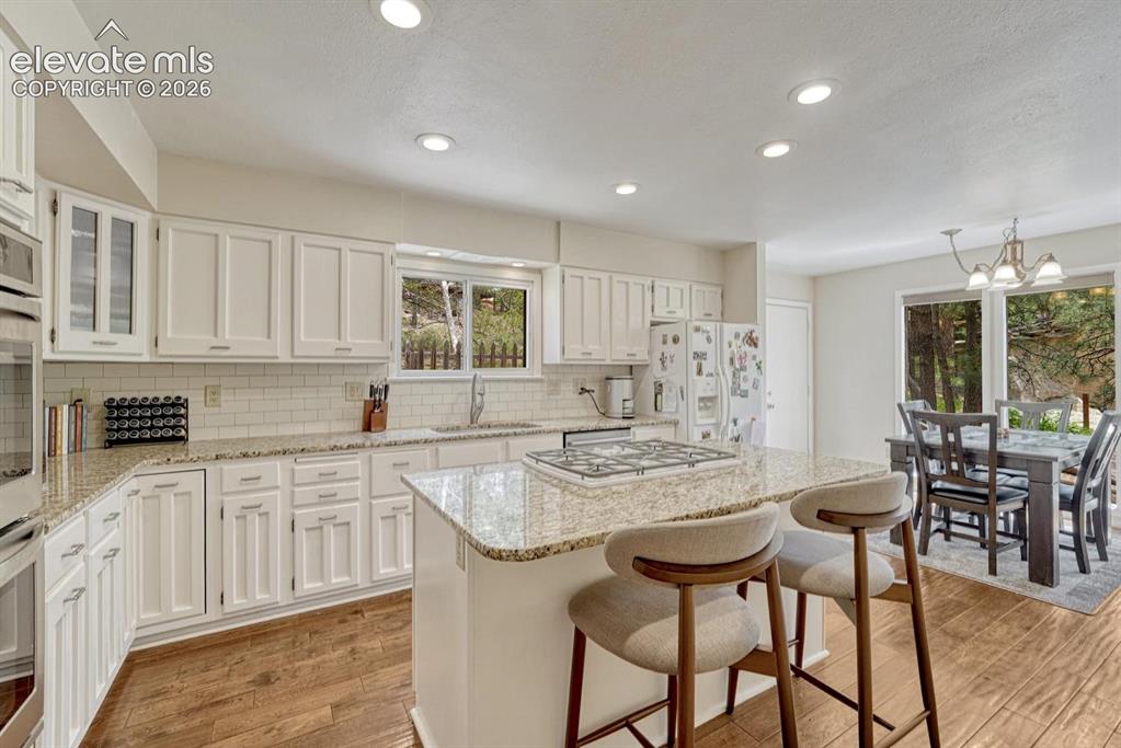 Image 10 of 48: Open-concept kitchen featuring white cabinetry, featuring a central island