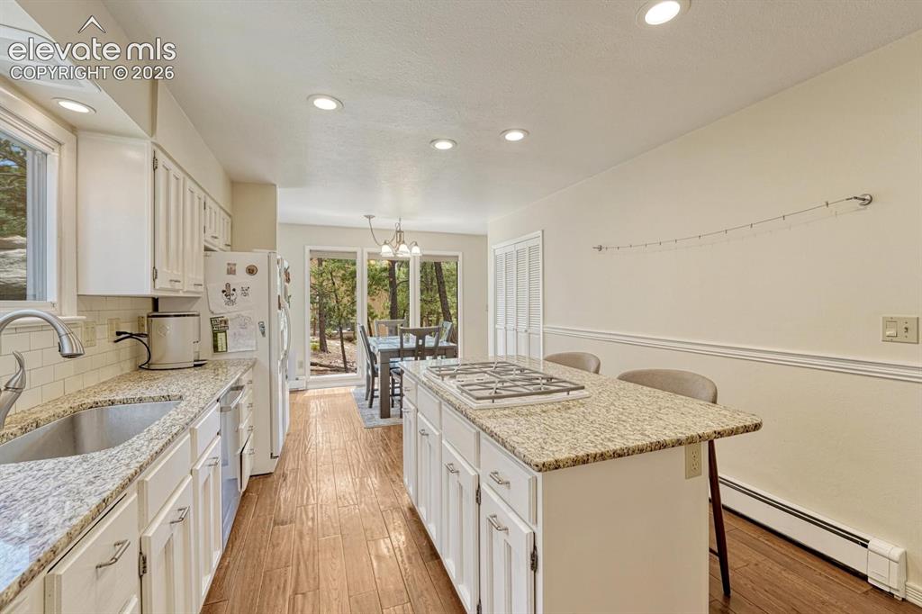 Image 11 of 48: Kitchen featuring granite countertops, a central island with an integrated