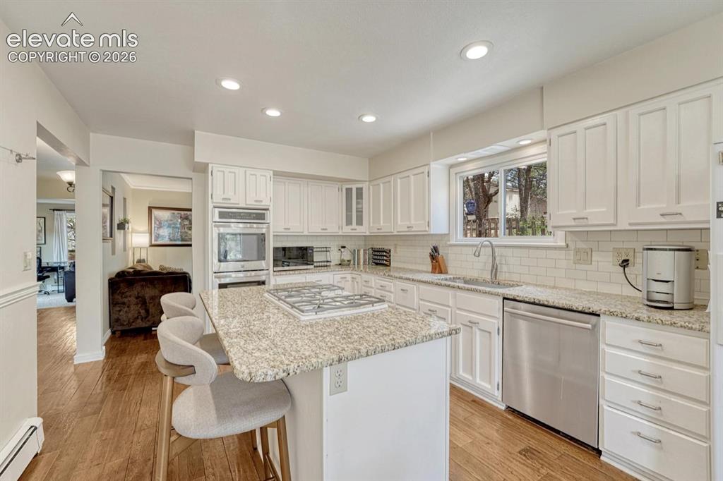 Image 12 of 48: Kitchen featuring a central island with cooktop, granite countertops, white