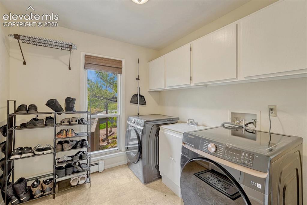 Image 14 of 48: Dedicated laundry area featuring abundant cabinetry, a window with natural