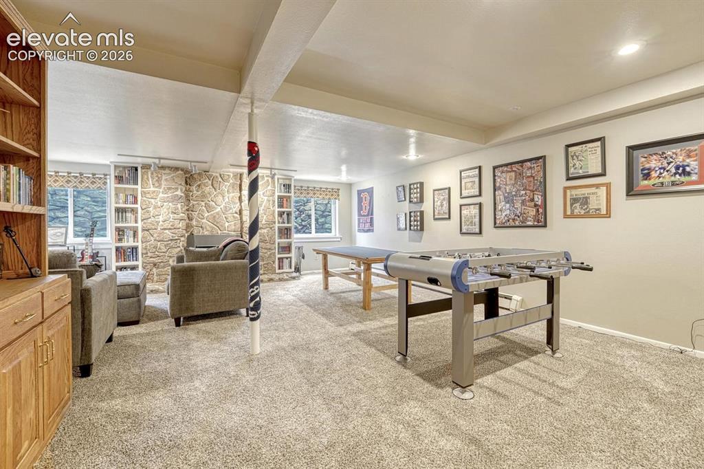 Image 15 of 48: Carpeted lower-level room featuring a prominent stone wall with a built-in