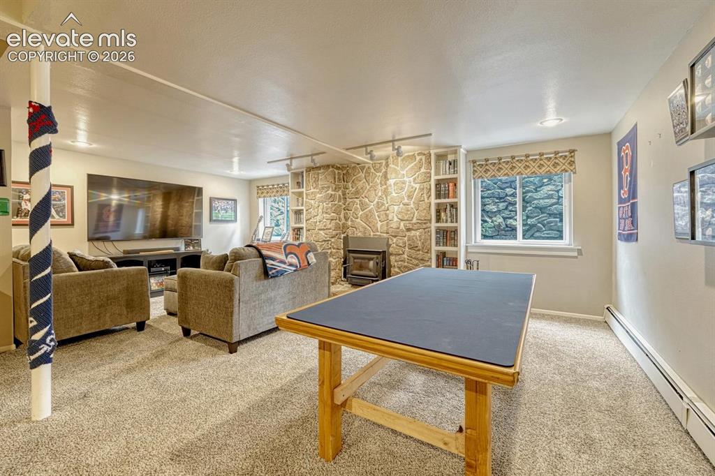 Image 16 of 48: Carpeted lower-level room featuring a prominent stone wall with a built-in