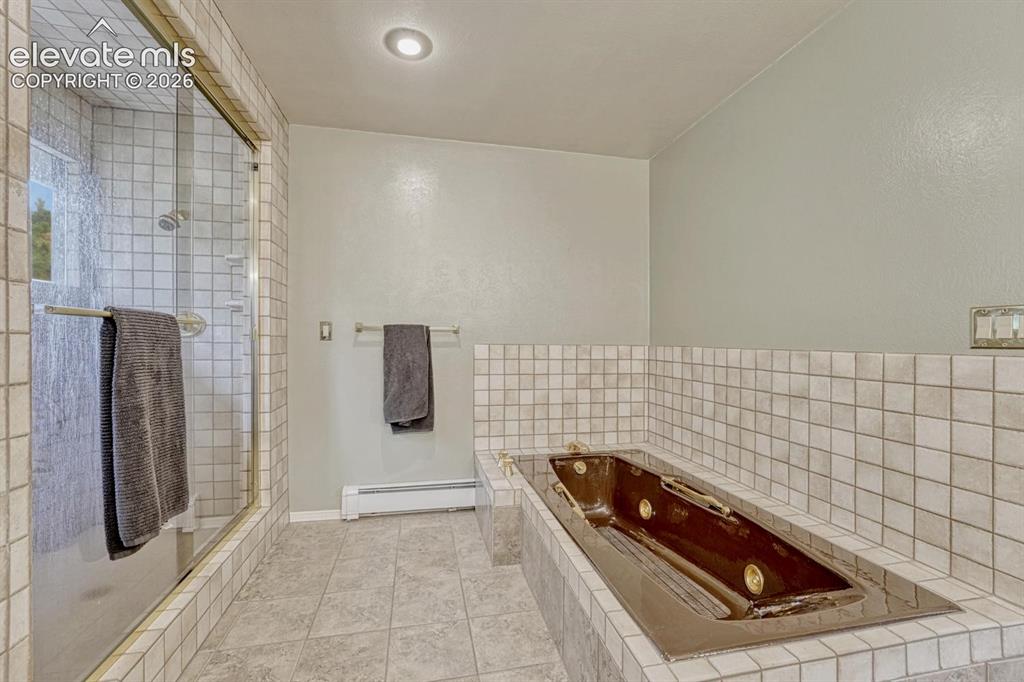 Image 27 of 48: Bathroom featuring a built-in soaking tub, tiled surround, and a glass-encl