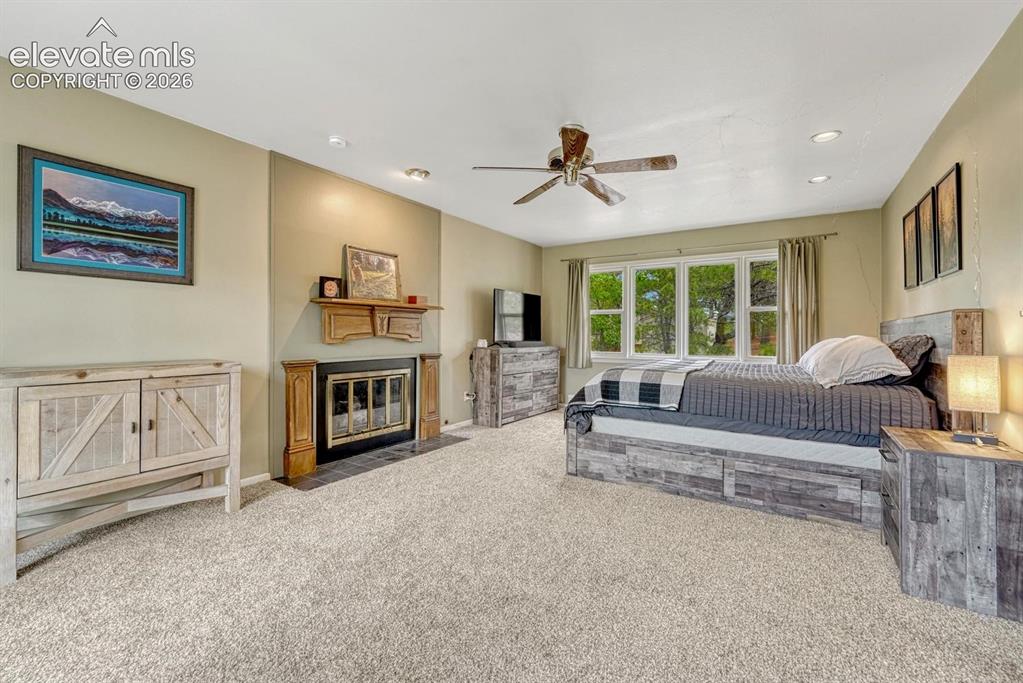 Image 28 of 48: featuring a ceiling fan, recessed lighting, a fireplace with a wood mantle
