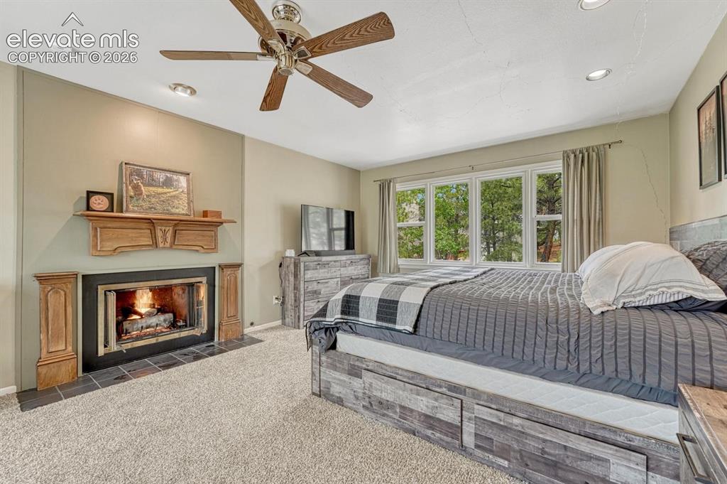 Image 31 of 48: Carpeted room featuring a fireplace with a wood mantle and black tile heart