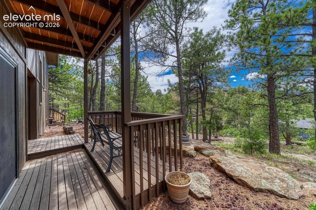 Image 34 of 48: Expansive covered porch featuring wood decking and a sturdy railing system