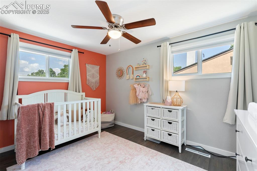 Image 14 of 39: Bedroom with a nursery area, dark wood-type flooring, and a ceiling fan