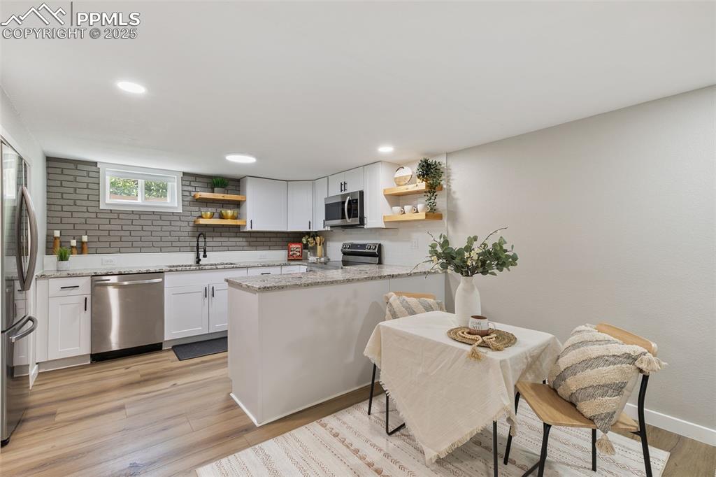 Image 21 of 39: Kitchen featuring open shelves, backsplash, light stone countertops, light