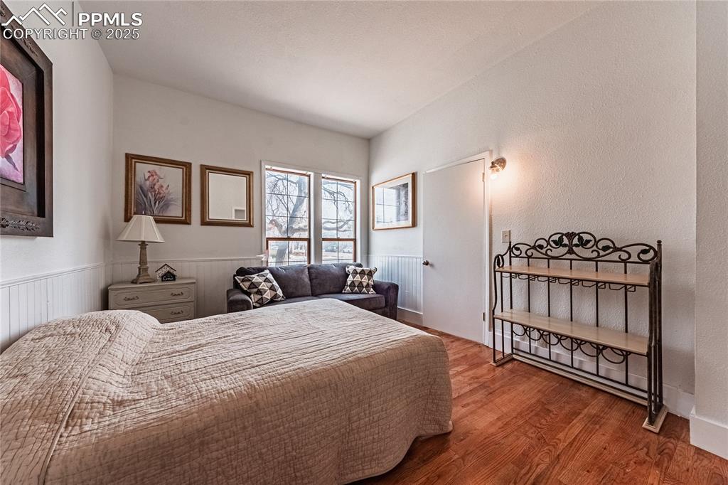 Image 24 of 39: Bedroom with wood finished floors and a wainscoted wall