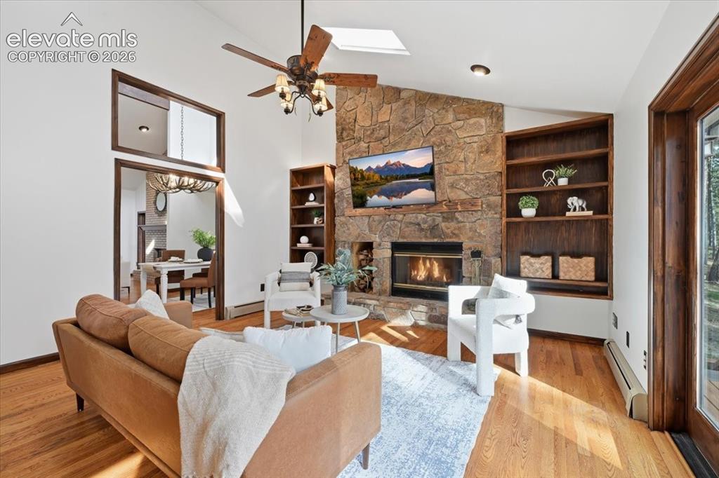 Image 11 of 46: Vaulted ceiling with a skylight and ceiling fan, stone-faced fireplace, har