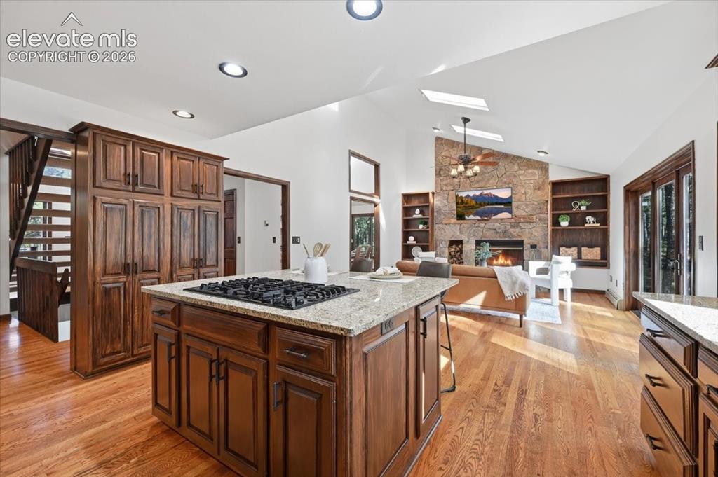 Image 13 of 46: Hardwood flooring, wood cabinetry, granite countertops, and a stone-faced f