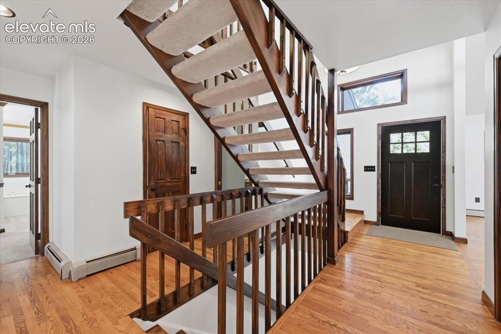 Image 19 of 46: Hardwood flooring, wood staircase with carpeted treads, dark wood entry doo