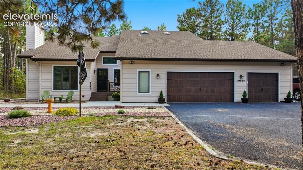 Image 2 of 46: Siding exterior with a multi-car garage, asphalt driveway, and a shingle ro
