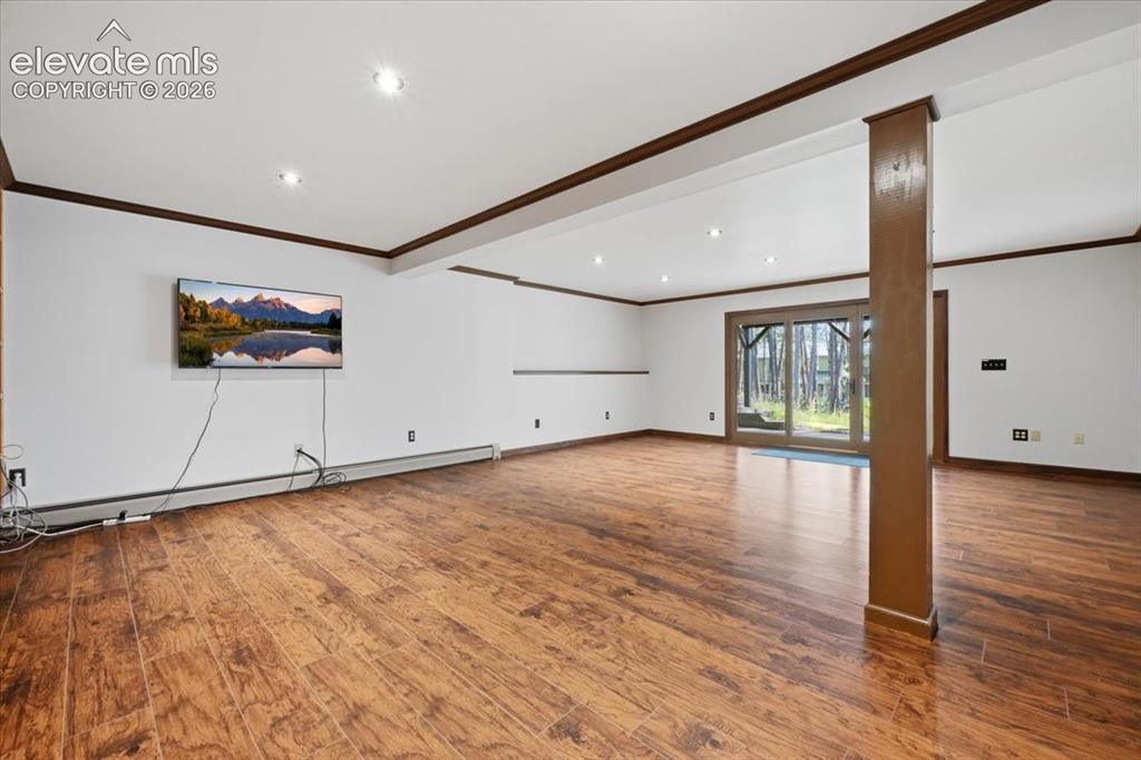 Image 26 of 46: Wood-finish flooring, recessed lighting, and white walls with dark trim