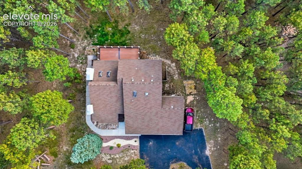 Image 3 of 46: Asphalt shingle roofing, skylights, and a private deck surrounded by mature
