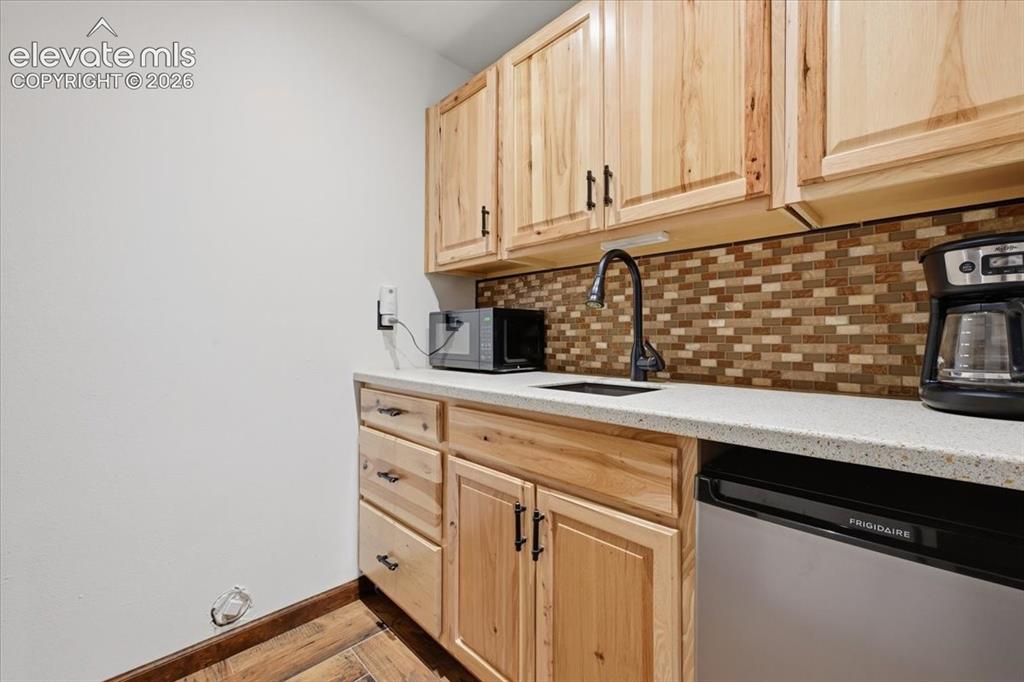 Image 33 of 46: Wood-finish cabinetry with dark hardware, stone-finish countertop, mosaic t