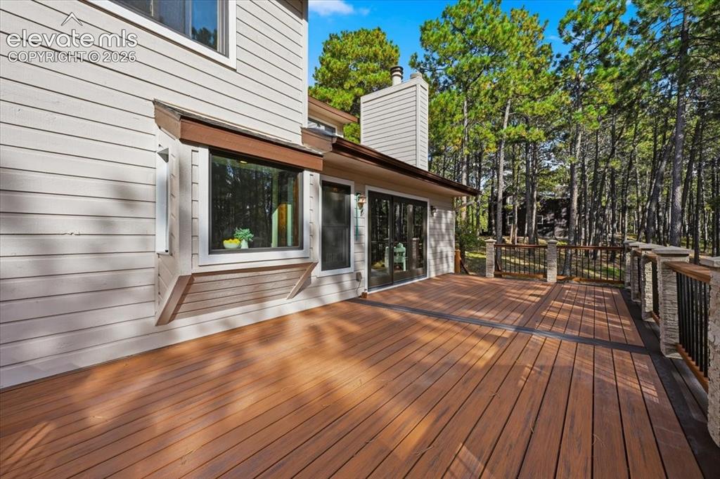 Image 40 of 46: Expansive multi-level deck, wood-finish flooring, stone pillars, wrought ir