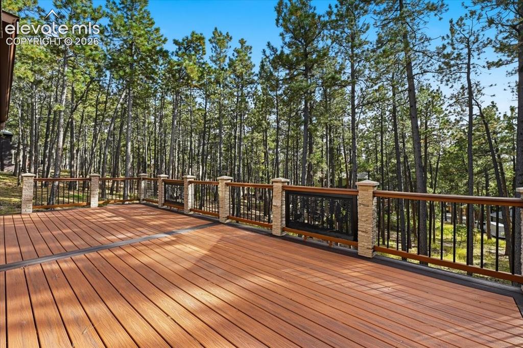 Image 41 of 46: Expansive composite deck with wood-finish planks, stone-clad railing posts,