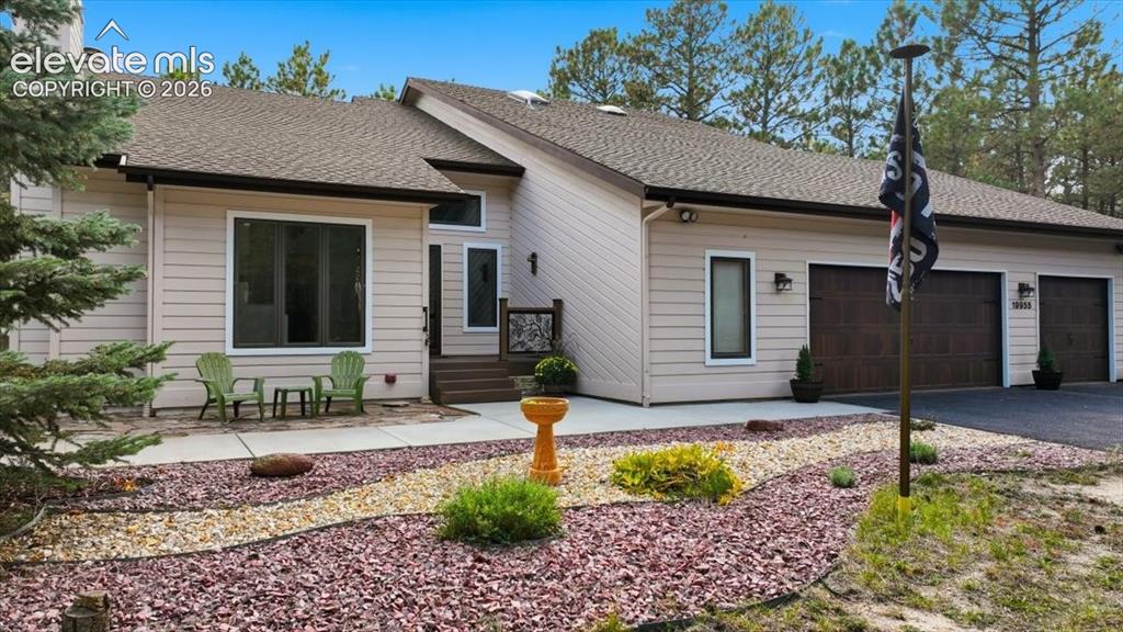 Image 44 of 46: Siding exterior with a multi-car garage, pitched shingle roof, and a landsc