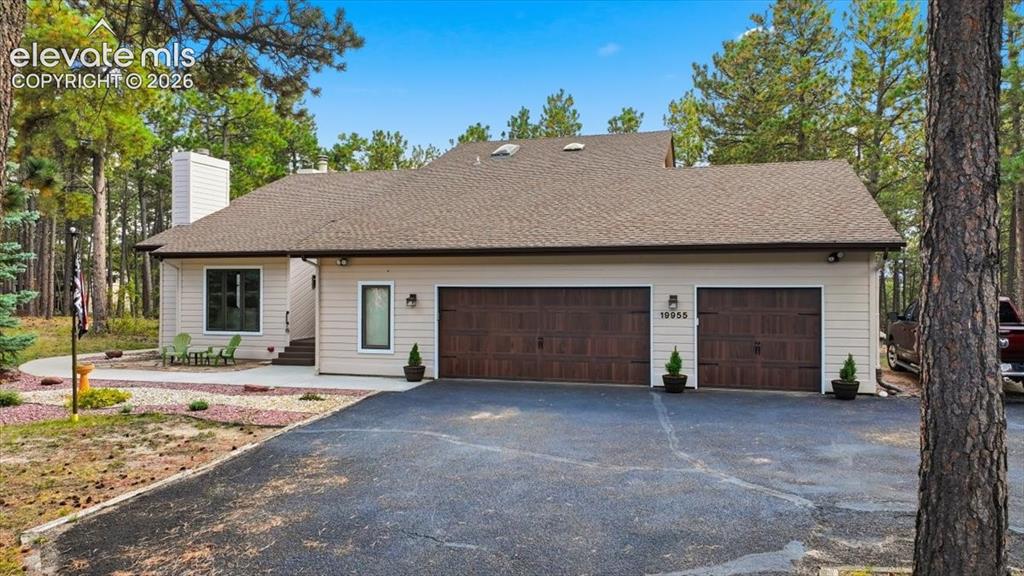 Image 45 of 46: Siding exterior with a neutral color palette, wood-finish garage doors, and