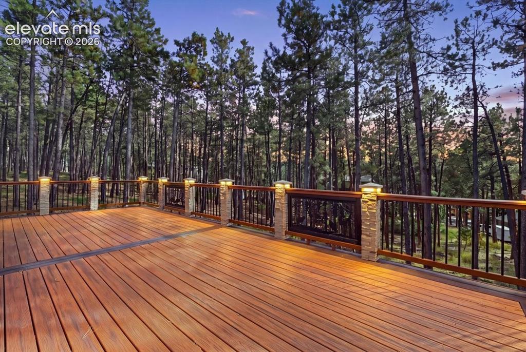 Image 5 of 46: Expansive outdoor deck featuring wood-finish decking, stone-clad pillars wi