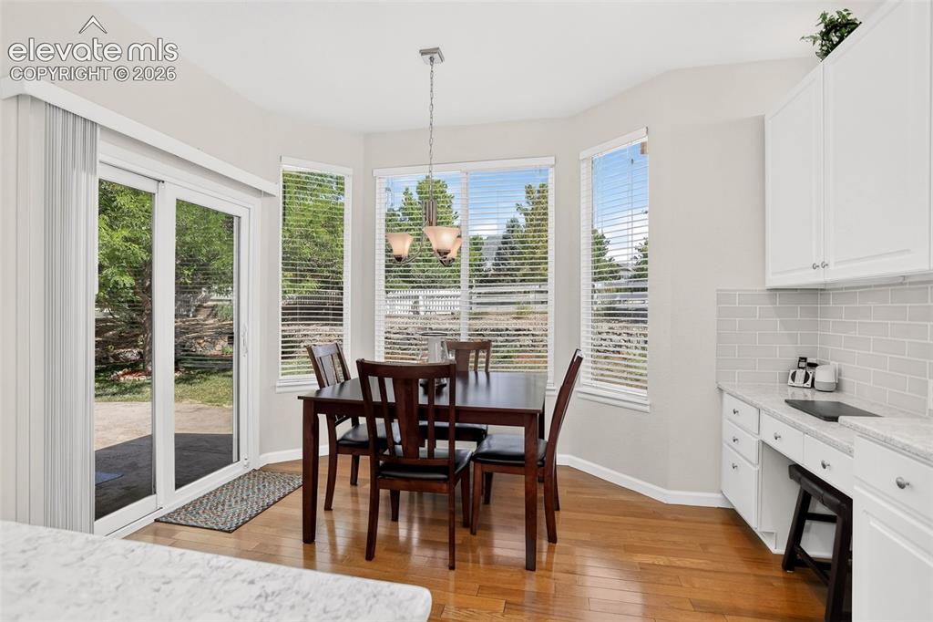 Image 12 of 42: Light-filled dining area featuring wood-finish flooring, a contemporary cha