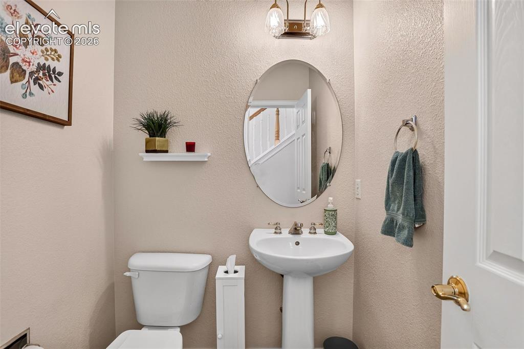 Image 18 of 42: Pedestal sink with dual-handle faucet, oval mirror, wall-mounted light fixt