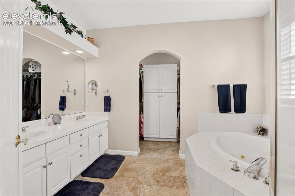 Image 21 of 42: Dual vanity with undermount sinks, an expansive mirror, and recessed lighti
