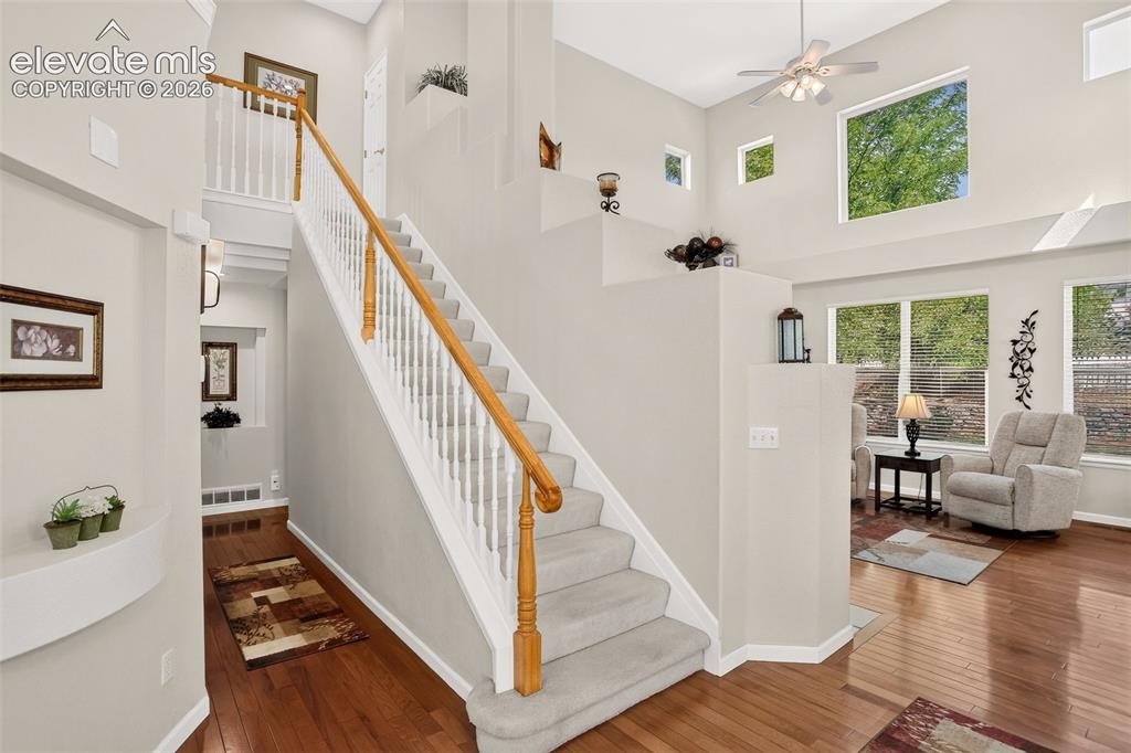 Image 25 of 42: Hardwood-finish flooring, carpeted staircase with white balusters and wood-