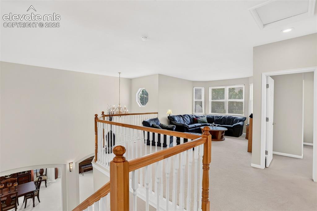 Image 26 of 42: Open landing with wood and white baluster railing, showcasing a chandelier,