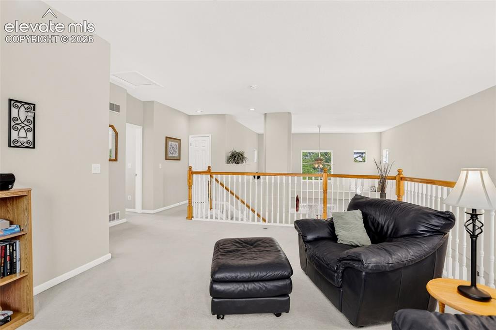 Image 28 of 42: Carpeted upper level with painted walls, white railing with wood handrail, 