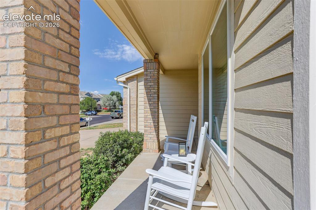 Image 3 of 42: Covered front porch featuring brick columns, horizontal siding, and a concr