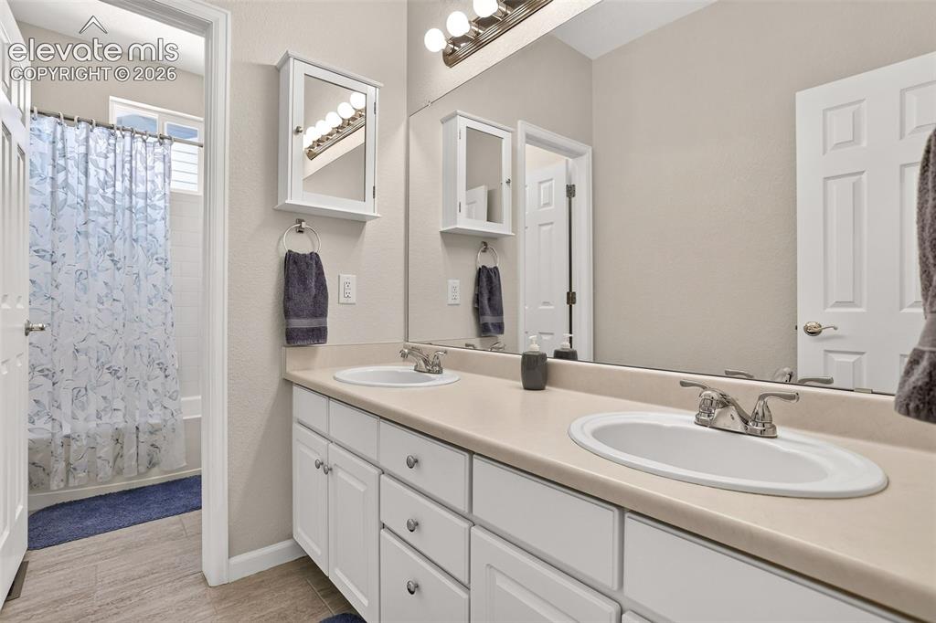 Image 31 of 42: Dual vanity with integrated sinks, white cabinetry, full-width mirror, and