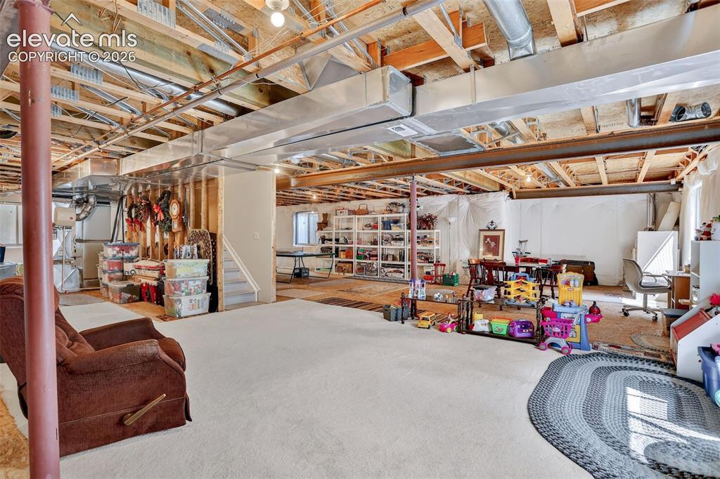 Image 35 of 42: Unfinished lower level featuring exposed ceiling joists and ductwork, a car