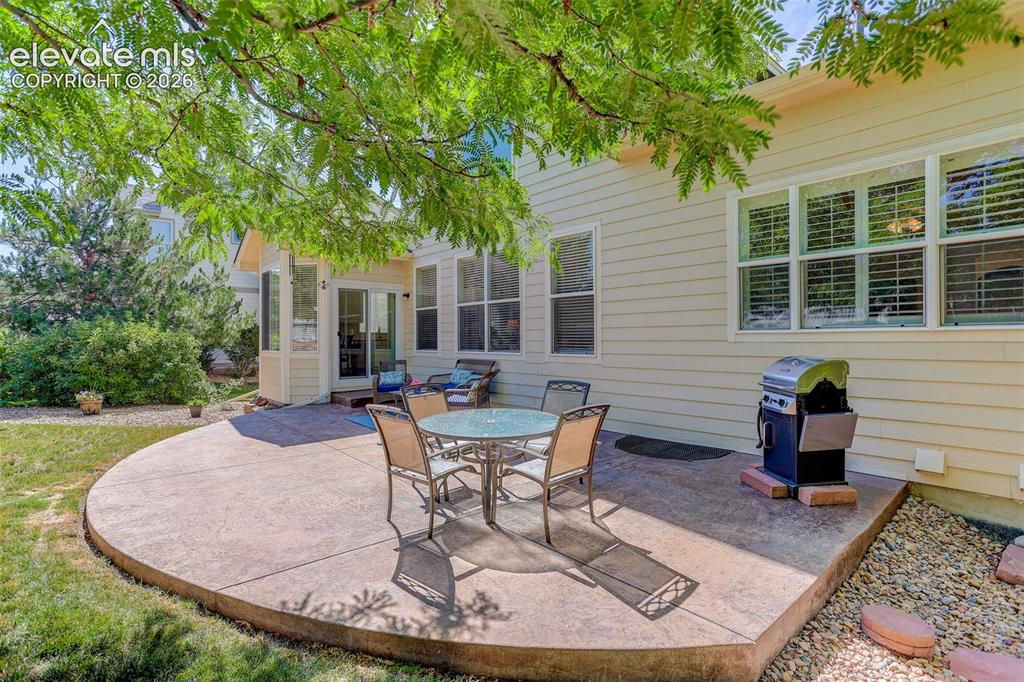 Image 37 of 42: Stained concrete patio with a curved edge, surrounded by a manicured lawn a
